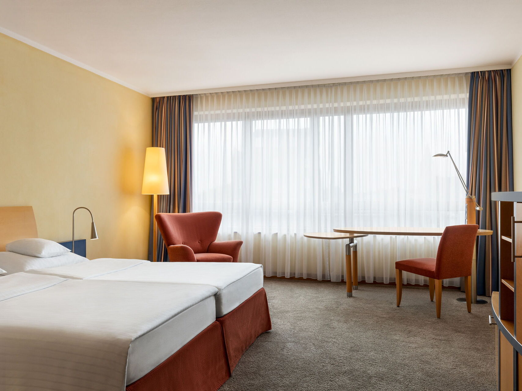 Double room with a double bed, armchair, TV, table, armchair, chair, and window