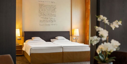 Hotel Remarque 2-Raum-Suite Schlafzimmer mit Doppelbett, Wandbild, Nachtschränken und Blumen