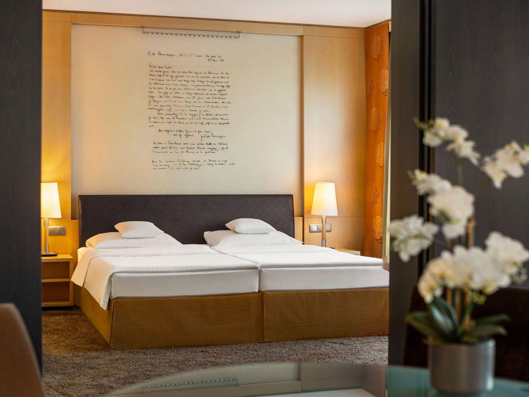 Hotel Remarque 2-Raum-Suite Schlafzimmer mit Doppelbett, Wandbild, Nachtschränken und Blumen