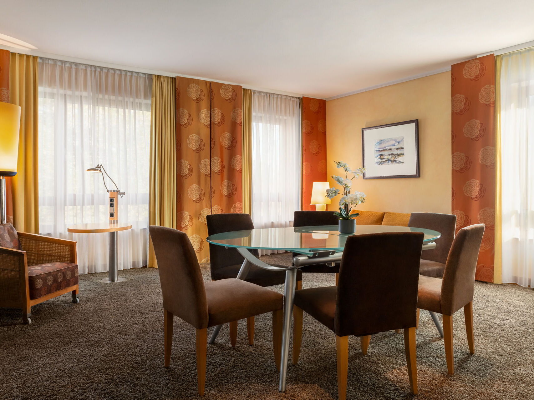 Hotel Remarque 2-Raum-Suite Wohnzimmer mit Tisch für 6 Personen, Stühlen, Wandbild, Stehlampe, Sessel