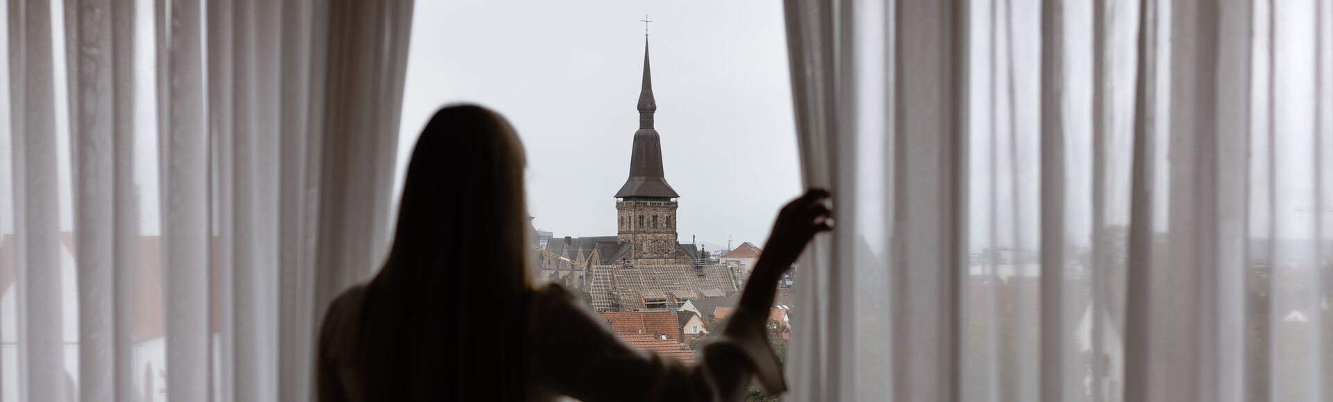 Woman looking out of a window of the Remarque Hotel onto Osnabrück city centre Woman looking out of a window of the Remarque Hotel onto Osnabrück city centre