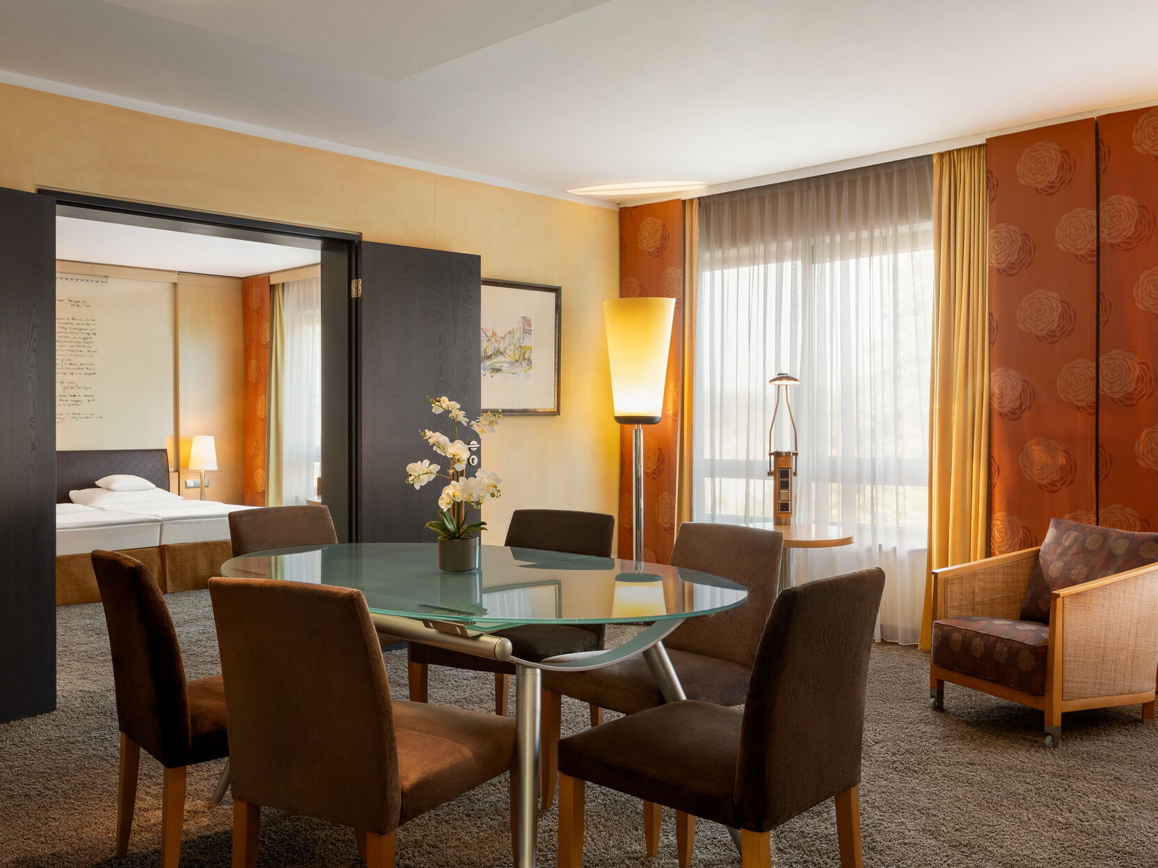 Hotel Remarque 2-Raum-Suite Wohnzimmer mit Tisch für 6 Personen, Stühlen, Wandbild, Stehlampe, Sessel